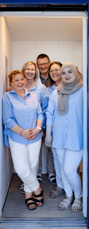 Alle Mitarbeiter lachend zusammenstehend